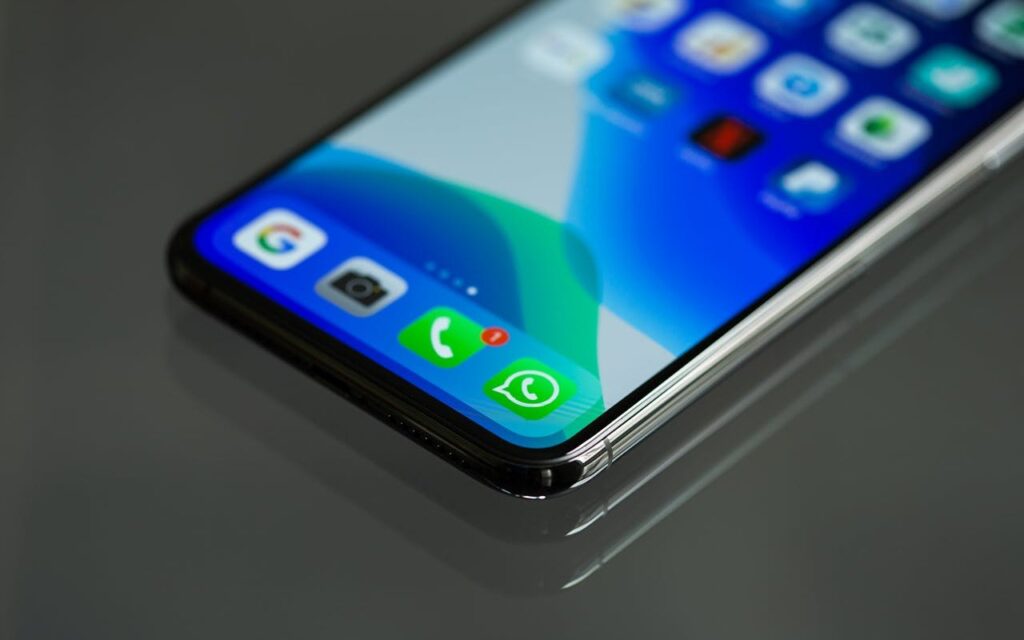 Mobilni telefon sa upaljenim ekranom na staklenom stolu